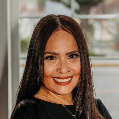 Close-up portrait of an individual with long straight hair smiling indoors